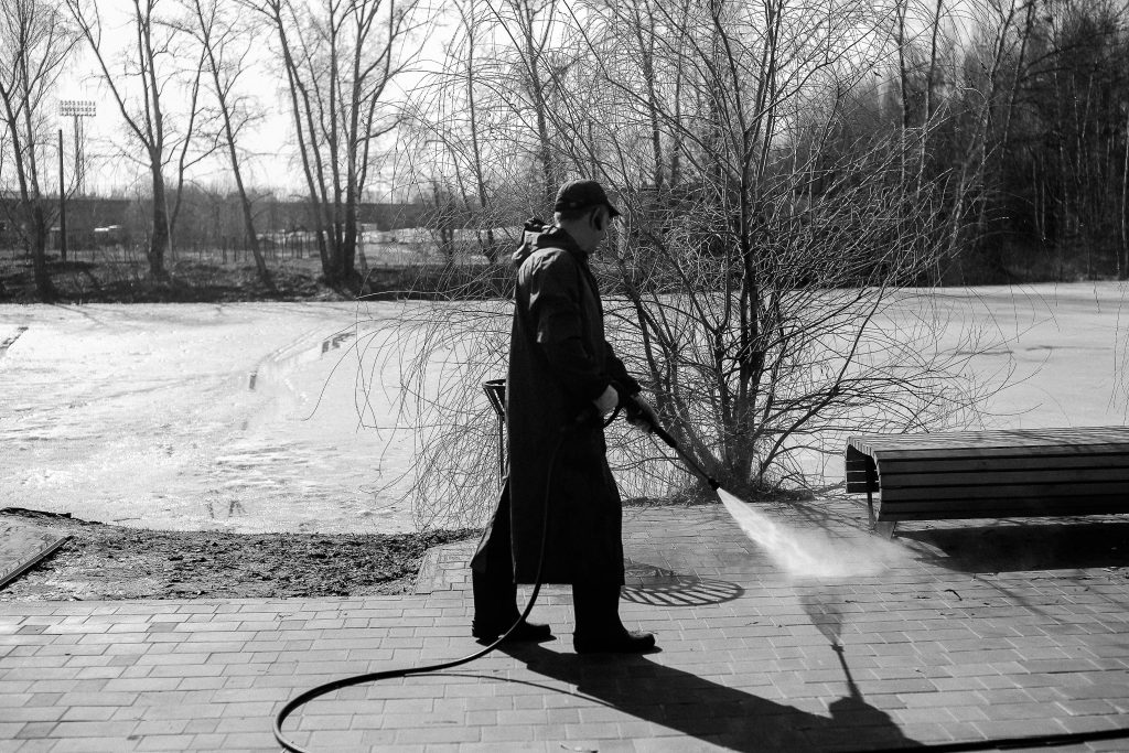 Person pressure washing stone patio